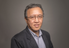 Headshot of Ron Wang, Ph.D. wearing a grey shirt